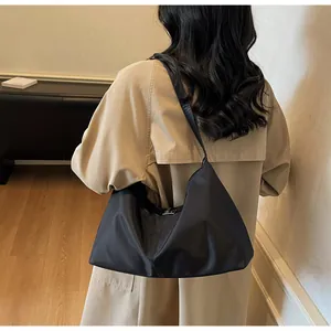 Close-up of minimalist black nylon tote bag with silver buckle and wide shoulder strap