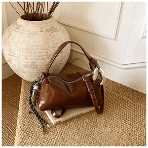 Detail of vintage brown leather pillow bag with silver buckle and braided charm decor