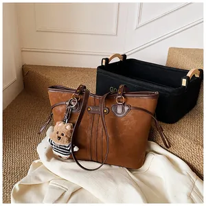 Vue détaillée du grand sac cabas marron avec texture daim, logo et pendentif ourson