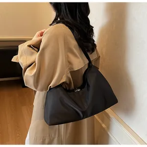 Detail of minimalist black nylon crescent tote bag showing the silver square metal lock clasp