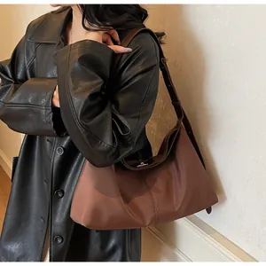 Detail of a brown nylon hobo bag with a leather shoulder strap on a model's shoulder