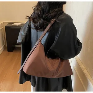 Lifestyle view of a brown leather crescent shoulder bag with adjustable strap details