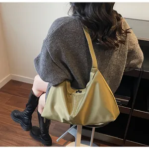 Olive green hobo tote bag with silver twist lock shown on a female model in a cozy interior