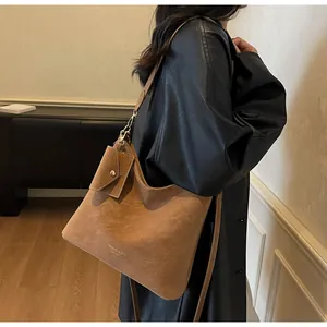 Detail of brown suede tote bag with gold logo lettering and small detachable coin purse