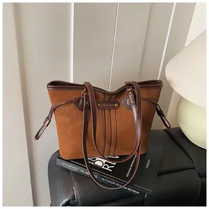 Détail d'un cabas en daim marron avec finitions en cuir et surpiqûres verticales