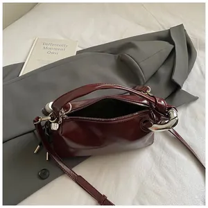 Close-up of deep red glossy leather handbag with chunky silver chain and dice pendant