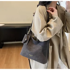 Close-up of a grey suede shoulder bag featuring gold lettering and small coin pouch
