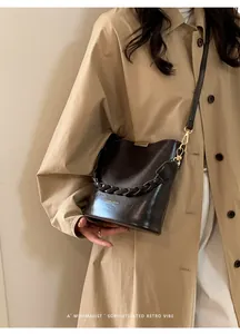 Detail of dark brown leather bucket bag with braided handle and gold metal hooks