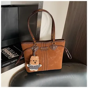 Détails du sac cabas en nubuck marron avec pendentif ours et logo de marque en métal