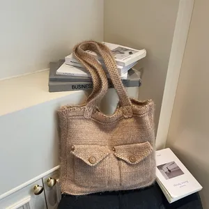 Grand sac cabas en maille avoine avec boutons décoratifs posé contre des livres
