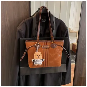 Sac cabas marron en daim avec anses en cuir et petit ours en peluche décoratif