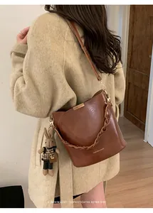 Close-up of retro brown bucket bag featuring woven handle and a cute rabbit charm detail