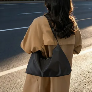 Minimalist black tote bag with silver buckle and shoulder strap in sunset street scene