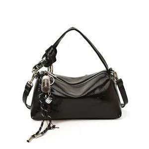 Glossy black vintage hobo bag with top handle and decorative charm on white background