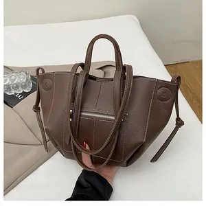 Detailed view of brown litchi pattern tote bag with white contrast stitching and side ties
