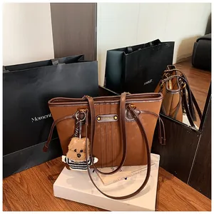 Gros plan du sac cabas en daim marron avec logo YOUN MADAM et charmant pendentif ours doux