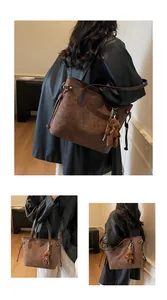 Detail of embossed tote bag with teddy bear charm and soft brown suede texture