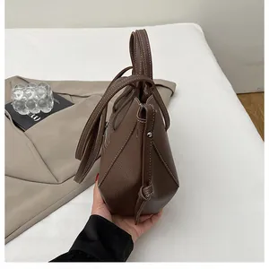 Detail of dark brown lychee grain leather tote bag with wing folding and metal hardware