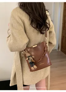Detail of brown vintage bucket bag with woven handle and plush rabbit charm