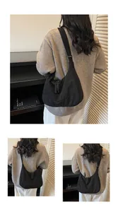 Detail of black large crescent shoulder bag with wide strap and woven knot zipper pull