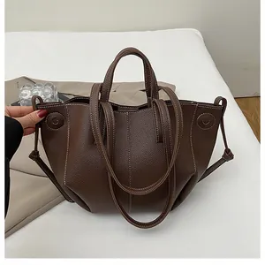 Detail of dark brown lychee leather bag with white contrast stitching and wing design