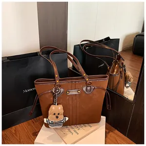Détail du grand sac cabas en daim marron avec garniture en cuir et porte-clés ours