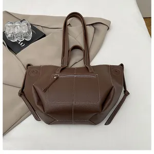 Detail of dark brown tote bag with white contrast stitching and litchi texture