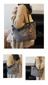 Detail shot of the gray embossed bear pattern and soft plush bear charm on the tote bag