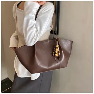 Detail of a large brown faux leather tote bag with stylish wooden bead tassel decoration