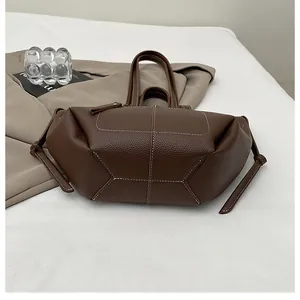 Detail of dark brown lychee leather tote bag with contrast stitching and drawstring decor