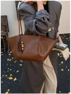 Close-up of vintage brown tote bag with smooth leather texture and wooden bead pendant