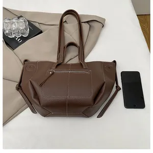 Brown litchi grain leather tote bag with white stitching showing large storage capacity