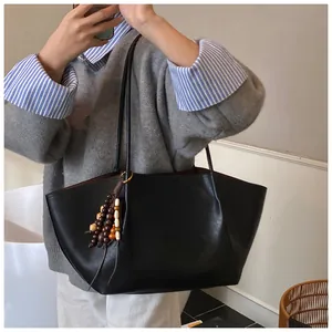 Detail of black matte leather tote bag with vintage wood bead tassel and long straps