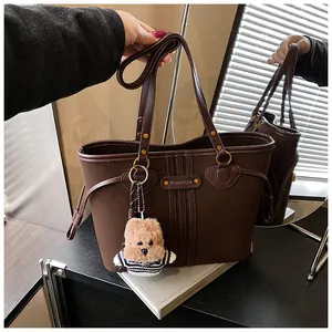 Détail du cabas en similicuir marron foncé avec rayures et pendentif ours en peluche