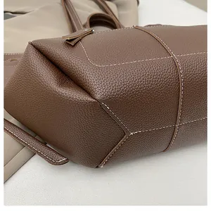 Detailed view of the chocolate brown lychee grain leather bag with white contrast stitching