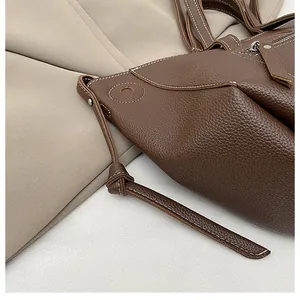 Detail of dark brown lychee leather bag featuring white contrast stitching and knotted strap