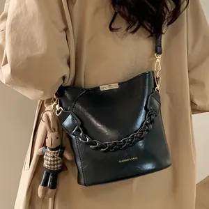 Vintage black leather bucket bag with gold metal trim and cute plush bunny charm