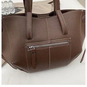 Detailed close-up of dark brown lychee pattern leather tote with white contrast stitching
