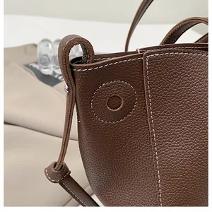 Detail of brown litchi leather bag showing white contrast stitching and grainy texture