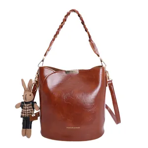 Retro brown bucket bag with woven handle and cute rabbit charm on white background