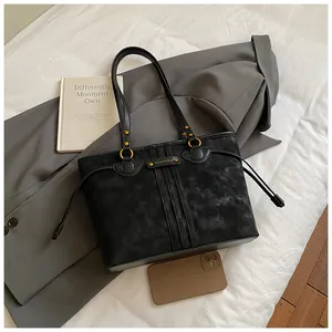 Détail du sac cabas en daim noir avec cordon de serrage et anneaux métalliques dorés