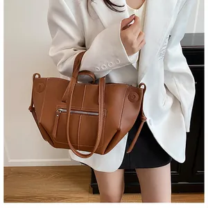 Detail of caramel lychee leather tote bag featuring white stitching and zipper pocket