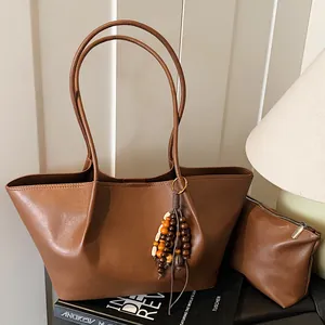 Brown leather tote bag with small pouch and stylish tassel in minimalist home setting