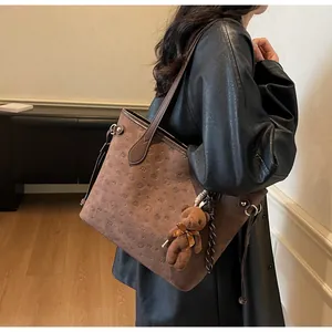 Close-up of embossed bear patterns on coffee brown tote bag with plush charm