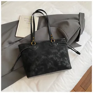 Détail d'un sac cabas noir avec anneaux dorés et cordons de serrage latéraux réglables