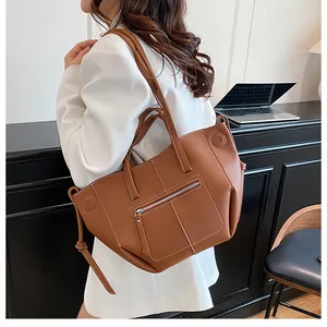 Detail view of caramel brown lychee leather tote bag with white stitching and silver zipper
