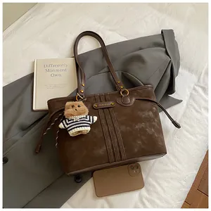 Détail du sac cabas marron foncé avec logo en métal, rivets et charmant petit ours