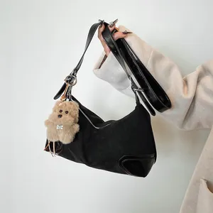 Minimalist black dumpling shoulder bag with plush bear charm and mixed texture design