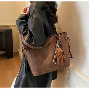 Detail of dark brown embossed tote bag with teddy bear charm and drawstring side
