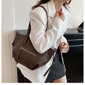 Detail of dark brown tote bag showing white contrast stitching and lychee leather texture